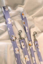 Two purple dog leashes with white flower patterns on a light fabric background