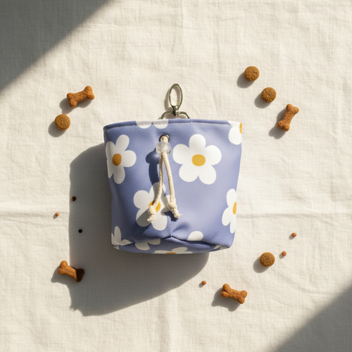 Small blue pouch with white daisy pattern on a light fabric background with scattered dog treats.